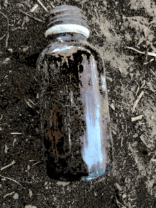 Flacon de sirop renversé, jeté par terre dans un environnement africain.