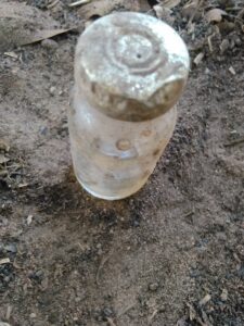 Flacon en verre abandonné sur le sol dans un environnement africain.