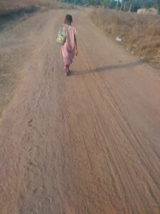 Une petite fille en tenue scolaire marchant joyeusement vers l\'école en afrique.