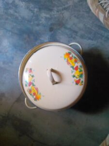 Bol en fer avec couvercle, décoré de motifs traditionnels africains, utilisé pour conserver ou servir les repas.