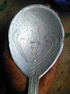 Grande cuillère africaine en fer ornée de motifs traditionnels gravés.