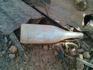 Grande bouteille abandonnée par terre, laissée sans surveillance dans un environnement extérieur.