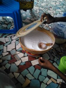Une calebasse remplie de lait de mouton avec une cuillère en calebasse posée dessus, vendue par une femme au village africain.