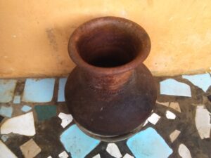 Canari en poterie avec un gobelet posé sur le dessus, utilisé pour stocker et servir des liquides dans les foyers traditionnels.