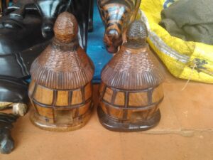 Deux petites maisons en bois sculpté et peint, représentant des structures traditionnelles africaines, utilisées comme objets décoratifs ou artisanaux.