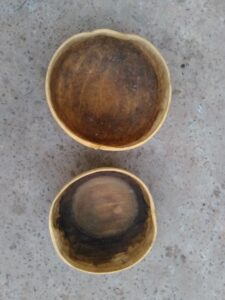 Deux calebasses posées par terre, utilisées dans la vie quotidienne en Afrique pour stocker des liquides ou comme récipients traditionnels.