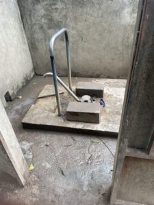 Ouvriers installant un forage d'eau dans un village rural africain, avec des enfants et des habitants locaux observant l'installation.