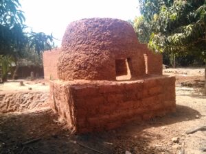 Un artisan construit un four en boue dans une région africaine, utilisant des techniques traditionnelles et des matériaux locaux
