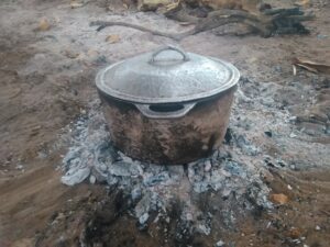ne marmite en train de cuire un plat sur un feu de charbon de braise, une méthode de cuisson traditionnelle et lente.