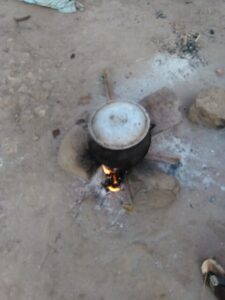 Marmite en cuisson sur un feu de bois, posée sur trois grosses pierres dans un village africain.
