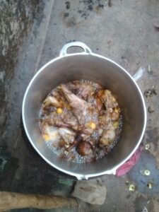 "Marmite en métal sur un feu, contenant une sauce de poulet mijotant dans de l'huile de palme."