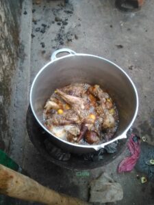 Une sauce au poulet mijotant dans une marmite posée sur un feu de bois, typique de la cuisine africaine.