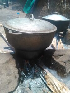 "Grande marmite en métal posée sur un feu de bois, prête à cuire."