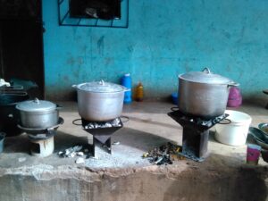 Trois marmites en métal posées sur des foyers africains, avec des flammes s'élevant du feu, illustrant la cuisine traditionnelle en plein air.