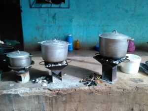 Trois marmites posées sur trois foyers au feu, chacune en train de cuire une sauce traditionnelle africaine.