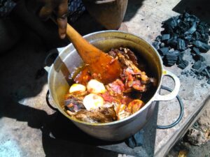 : Des marmites en train de cuire sur le feu, remuées pour une cuisson parfaite, une scène typique de la cuisine africaine traditionnelle.