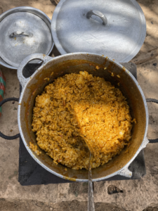 Du riz cuit mélangé avec une sauce savoureuse dans une marmite, un plat traditionnel africain en préparation.