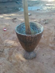 Mortier en bois avec pilon, utilisé pour moudre ou écraser des ingrédients dans la cuisine traditionnelle.