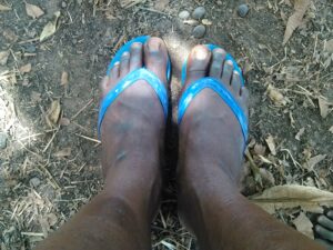 Les pieds d’un homme adulte reposant sur un repose-pied en caoutchouc, suggérant une posture de relaxation.