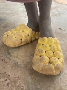 Un petit garçon africain, debout pieds nus sur un sol de terre