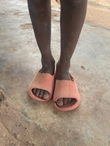 Pieds nus d’un enfant africain debout sur un sol de terre sèche
