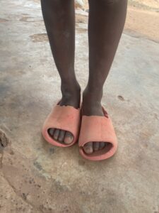 Les pieds d’un jeune garçon africain, debout pieds nus sur un sol terreux