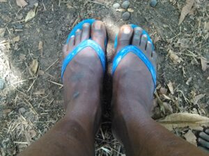 Les pieds d’un homme adulte reposant sur un repose-pied en caoutchouc bleu, suggérant un moment de détente.