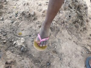 Pieds d’une enfant africaine, debout pieds nus sur un sol en terre