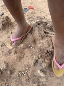 Les pieds nus d’une petite fille africaine sur un sol en terre