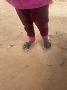 Jambes d’une petite fille portant un pantalon, pieds nus sur le sol