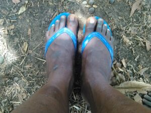 Les pieds d'un homme adulte posés sur un repose-pied en caoutchouc, montrant un moment de détente.