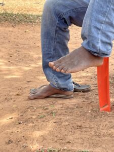 Pied nu d'un adulte africain posé sur un sol, avec des détails visibles de la peau et du terrain.