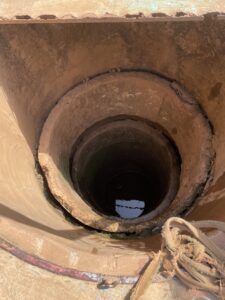 Puits profond en Afrique, avec des personnes utilisant des seaux pour puiser de l'eau.