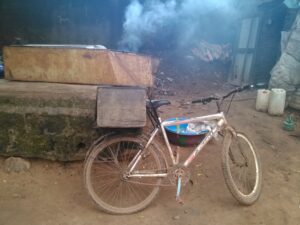 Vendeur de pain sur un vélo dans une rue d'Afrique, avec des paniers de pain sur le porte-bagages.