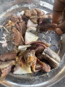 Assortiment de viandes (côtelettes, saucisses, steaks) grillées sur un barbecue, avec une légère fumée s'échappant des braises.