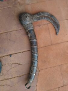 Faucille traditionnelle africaine pour la récolte du riz, avec manche en bois et lame en métal, exemple d'artisanat.