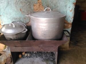 Grande marmite ouverte sur un fourneau de charbon ardent pour une cuisson familiale en Afrique.