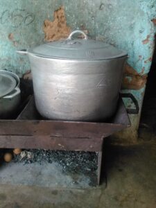 Grande marmite sur un fourneau de charbon ardent, scène de cuisson familiale en Afrique.