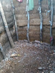 Photo ou dessin d'une structure de douche extérieure entièrement faite de paille, dans un village africain.