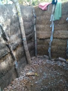 Dessin ou photo d'une structure de douche extérieure faite de paille, dans un village africain.