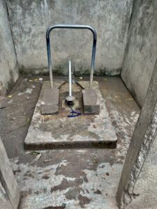 Représentation d'un forage d'eau avec pompe manuelle, utilisé par des villageois en Afrique.