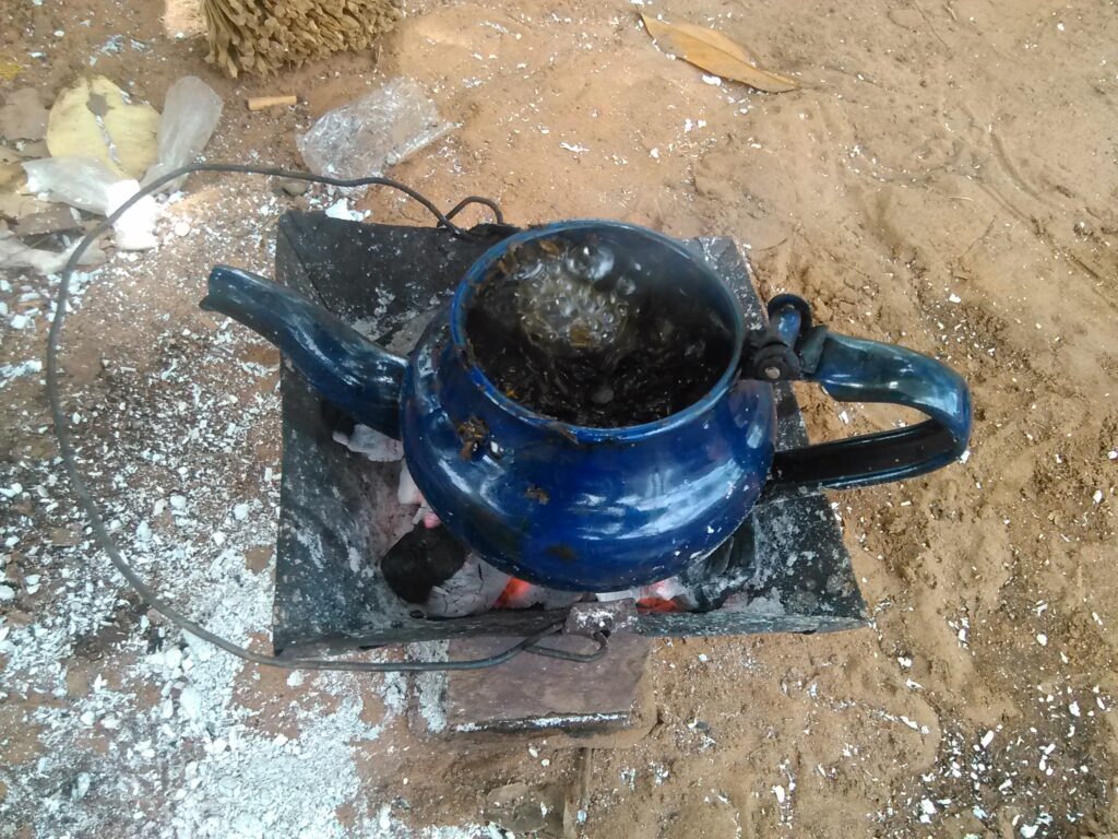 Image d'une petite cafetière sur un fourneau artisanal chauffé au charbon en Afrique