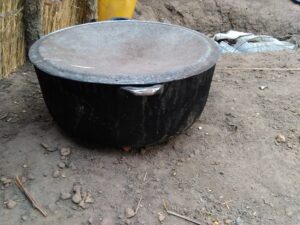 Image d'une grande marmite en métal ou en terre cuite, utilisée dans un contexte africain