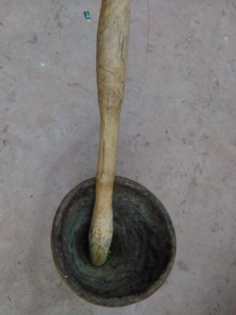 Un petit mortier et pilon en bois, utilisé pour moudre des épices africaines, posé sur une surface en bois.