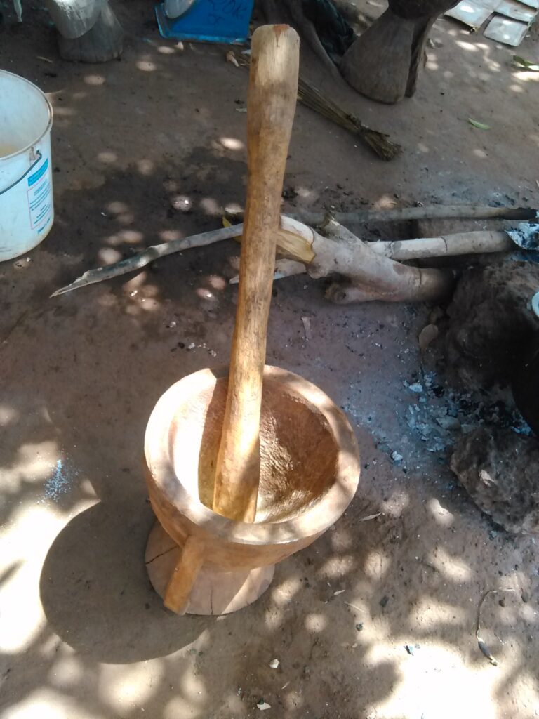 Un petit mortier et pilon en bois traditionnel utilisé pour moudre des épices africaines, posé sur une surface en bois.