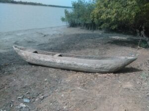 Pirogue en bois attachée et laissée à l’abandon au bord d’un fleuve africain, à proximité d’un village