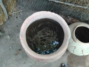 Un grand canari en terre cuite rempli d'eau, situé dans un village africain traditionnel