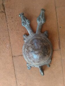 Une sculpture artisanale en métal représentant une tortue à deux têtes, typique de l'artisanat africain.